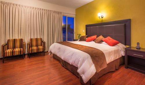 a bedroom with a large bed and two chairs at Hotel Patzcuaro in Pátzcuaro