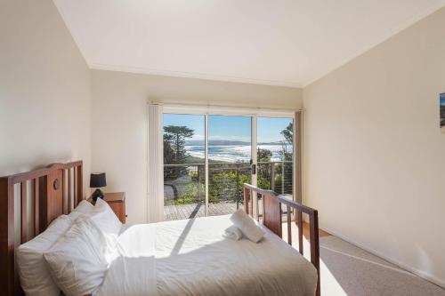 a bedroom with a bed and a large window at Surfside in Pambula Beach