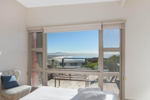 a bedroom with a bed and a view of a balcony at The Love Shack in Pambula