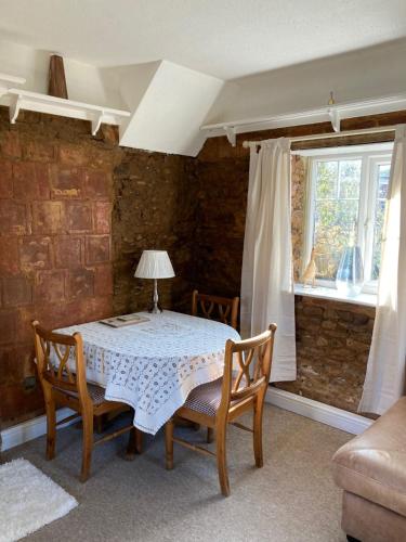 a dining room with a table and chairs and a window at Holcot Cottage 