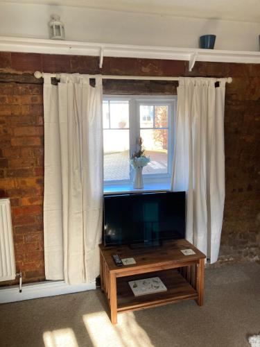 ein Wohnzimmer mit einem TV und einem Fenster in der Unterkunft Holcot Cottage 