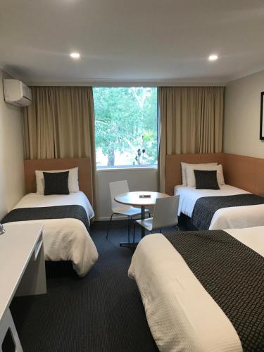 a hotel room with three beds and a table at Parkview Motor Inn and Apartments in Wangaratta