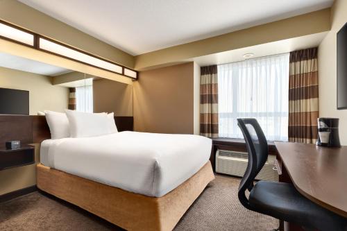 a hotel room with a bed and a desk at Microtel Inn & Suites by Wyndham Estevan in Estevan