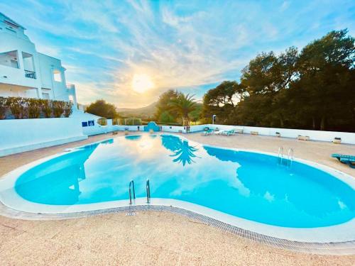 una gran piscina azul frente a un edificio en Apartamento Brisa de Menorca, en Son Parc
