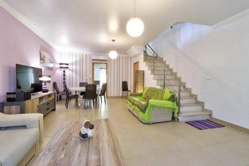 a living room with a green couch and a staircase at MORADIA DO SOL in Olhão