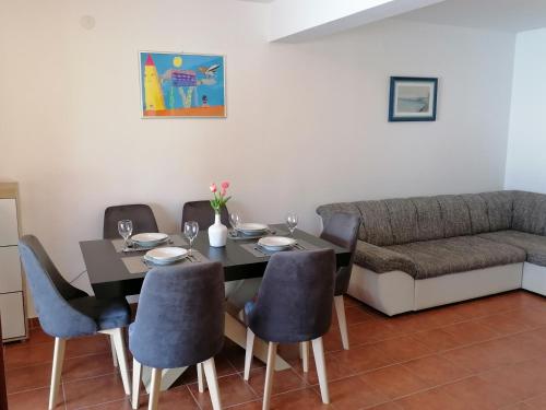 a dining room with a table and chairs and a couch at Apartment D&D in Prigradica