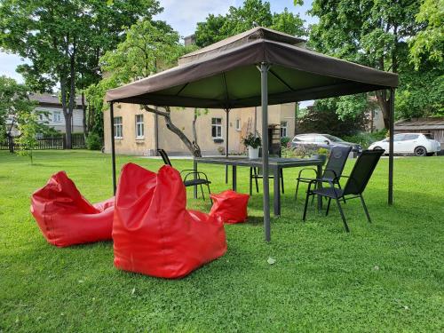 two red chairs and a table under an umbrella at Studio apartment in private house in Rīga
