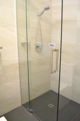 a shower with a pull sign in a bathroom at Busselton Ithaca Motel in Busselton