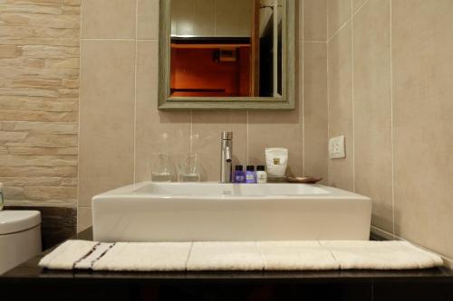 a bathroom with a white sink and a mirror at Namtok Sarika Resotel in Nakhon Nayok
