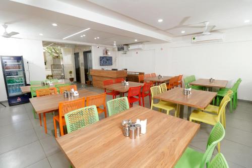 a restaurant with wooden tables and colorful chairs at Nova Sahaj Residency in Khirasra
