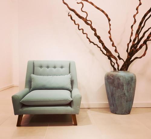 a green chair and a vase with a plant at AQUA Boutique Hotel in Glacis