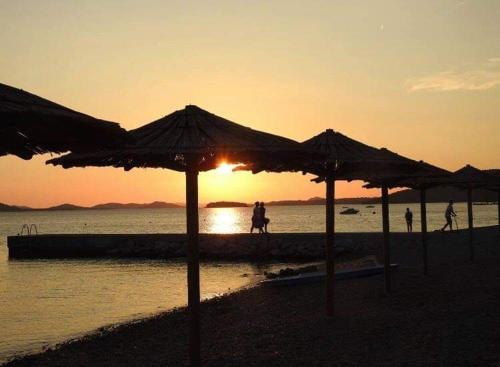 a group of umbrellas on the beach at sunset at Apartman AS in Pirovac