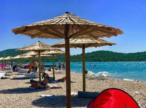 a group of people laying on a beach under umbrellas at Apartman AS in Pirovac