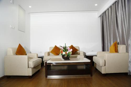 a living room with two couches and a coffee table at Triguna Clarks Inn Kurnool in Kurnool