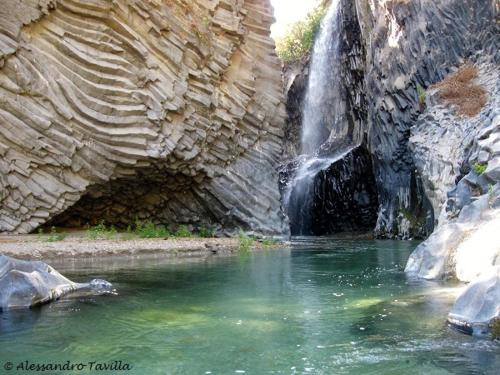 a waterfall with a pool of water in front of a mountain at vacanza Taormina mare in Mazzeo