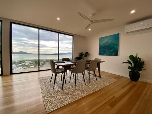 a dining room with a table and chairs and large windows at Luxury Villas Townsville in Belgian Gardens