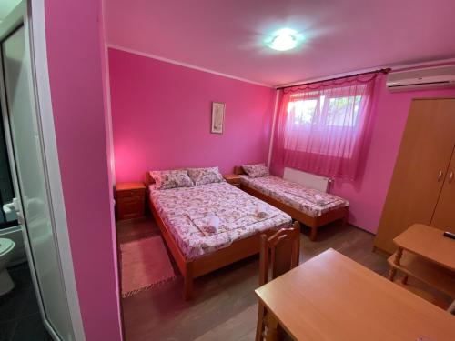 a room with two beds and a pink wall at Vila Fontana - Sobe in Bela Crkva