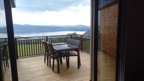 a table and chairs on a balcony with a view of the water at Ferienwohnungen Schöbringer in Weyregg