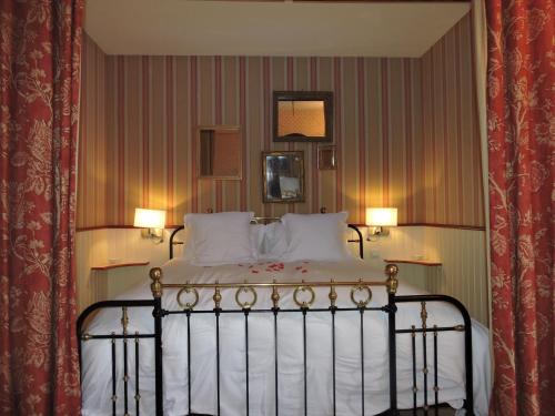 a bedroom with a bed with white sheets and pillows at Le Domaine de Mestré, The Originals Relais in Fontevraud-l'Abbaye