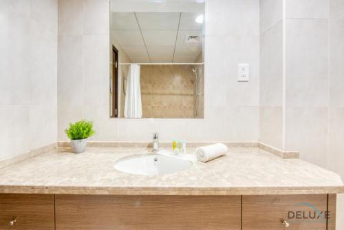 a bathroom with a sink and a mirror at Sunny 1BR at Canal Residences West Dubai Sports City by Deluxe Holiday Homes in Dubai