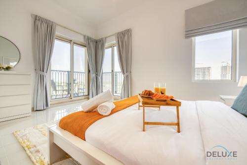 a white bedroom with a large bed and windows at Sunny 1BR at Canal Residences West Dubai Sports City by Deluxe Holiday Homes in Dubai