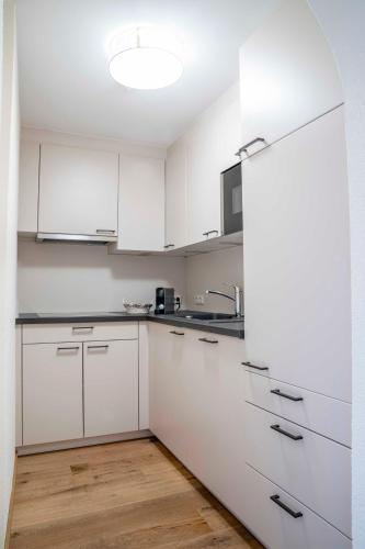 a white kitchen with white cabinets and a wooden floor at Hotel Montana in Fiss