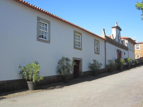 a white building with potted plants on a street at Quinta das Aranhas in Castelo de Paiva