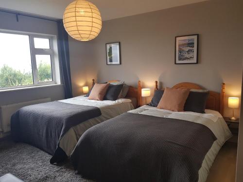 EadargóilにあるCois Farraigeの窓とシャンデリアが備わる客室で、ベッド2台が備わります。