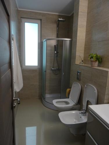 een badkamer met een douche, een toilet en een wastafel bij Apartament Monicos in Năvodari