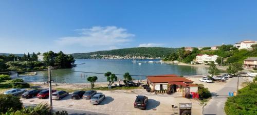 a group of cars parked in a parking lot next to a lake at Apartmani Premijer-Rab in Supetarska Draga