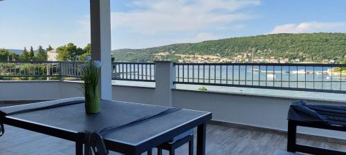 a table on a balcony with a view of the water at Apartmani Premijer-Rab in Supetarska Draga