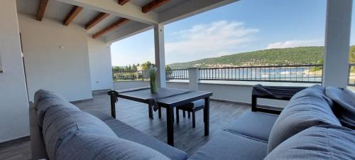 a living room with a couch and a table on a balcony at Apartmani Premijer-Rab in Supetarska Draga