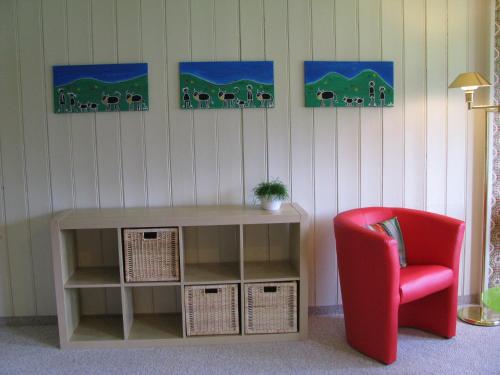 a living room with a red chair and a table at Zimmer & z'Morgä Schönenboden in Wildhaus