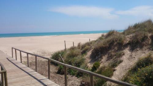 a wooden boardwalk leading to a beach with the ocean at UIM Mediterraneo ATICO Poeta 7 Wifi in Puerto de Sagunto