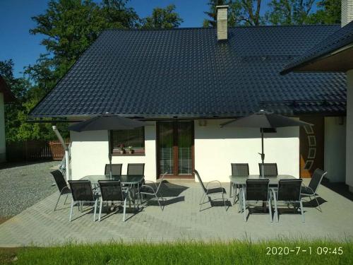 a patio with chairs and tables and umbrellas at Apartmány u Beka in Loučná nad Desnou