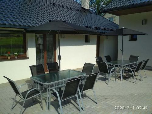 a patio with two tables and chairs and an umbrella at Apartmány u Beka in Loučná nad Desnou