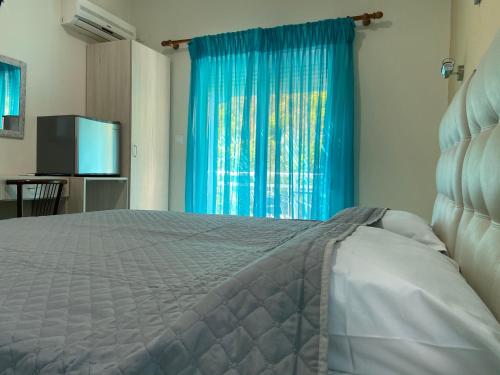 a bedroom with a bed and a blue curtain at Samothraki Akrogiali Rooms in Samothráki