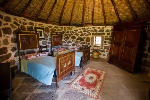 1 dormitorio con 2 camas y pared de piedra en Pinnettu Ghilarza, en Ghilarza