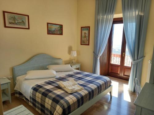 a bedroom with a bed with a checked blanket and a window at L'Antico Monastero in SantʼAgata di Puglia