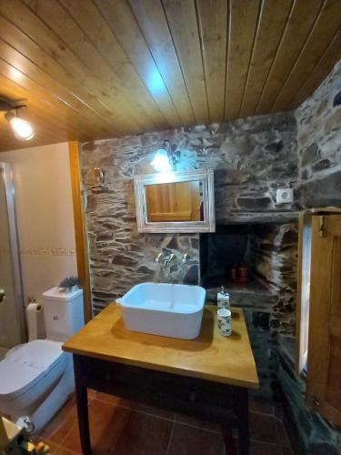 a bathroom with a sink and a stone wall at Talasnal Casas da Urze TER in Lousã