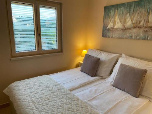 a white bed in a room with a window at Villa Luka Lopar in Lopar