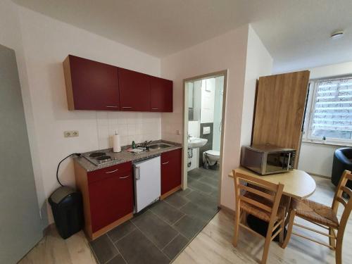 eine Küche mit roten Schränken und einem Tisch mit einer Mikrowelle in der Unterkunft Ferienwohnung Kranichnest in Neddesitz