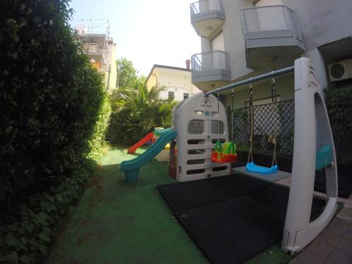 a playground in front of a house with a slide at Residence Villa Azzurra in Rimini