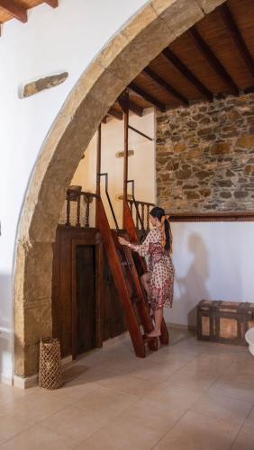 a woman is sitting on the stairs in a building at Anesis Traditional Rhodian House in Kattavía