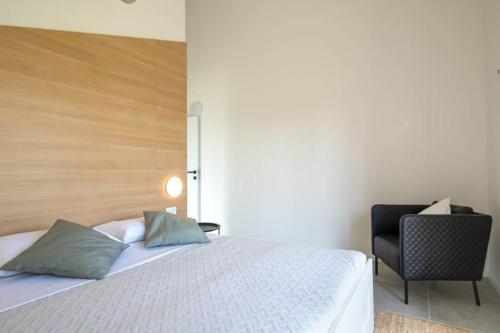 a bedroom with a white bed and a chair at Villa Mateo with heated pool in Fažana
