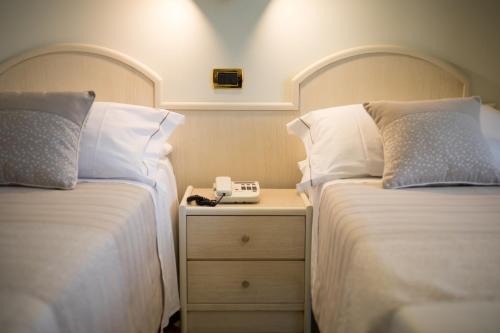 a hotel room with two beds and a nightstand between them at Hotel Gardenia Sorrento, Ascend Hotel Collection in Sorrento