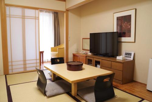 a living room with a table and a television at Hotel Hokke Club Osaka in Osaka