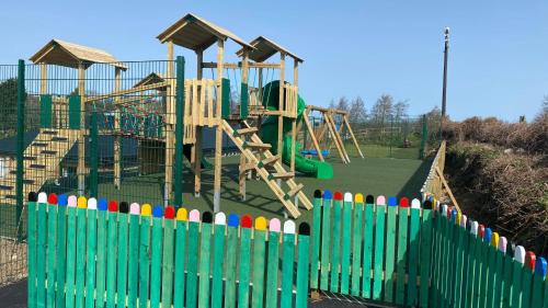 a playground with a green fence and a play structure at Beamish Holiday Park in Stanley