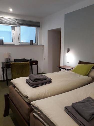 two beds in a room with a desk and a table at Ferienwohnung Sonnentau 2 in Holzminden