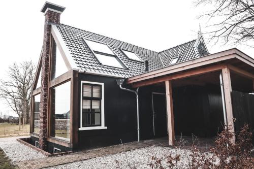 een zwart huis met een gambrel dak bij Gastenverblijf lânlibben in Lioessens